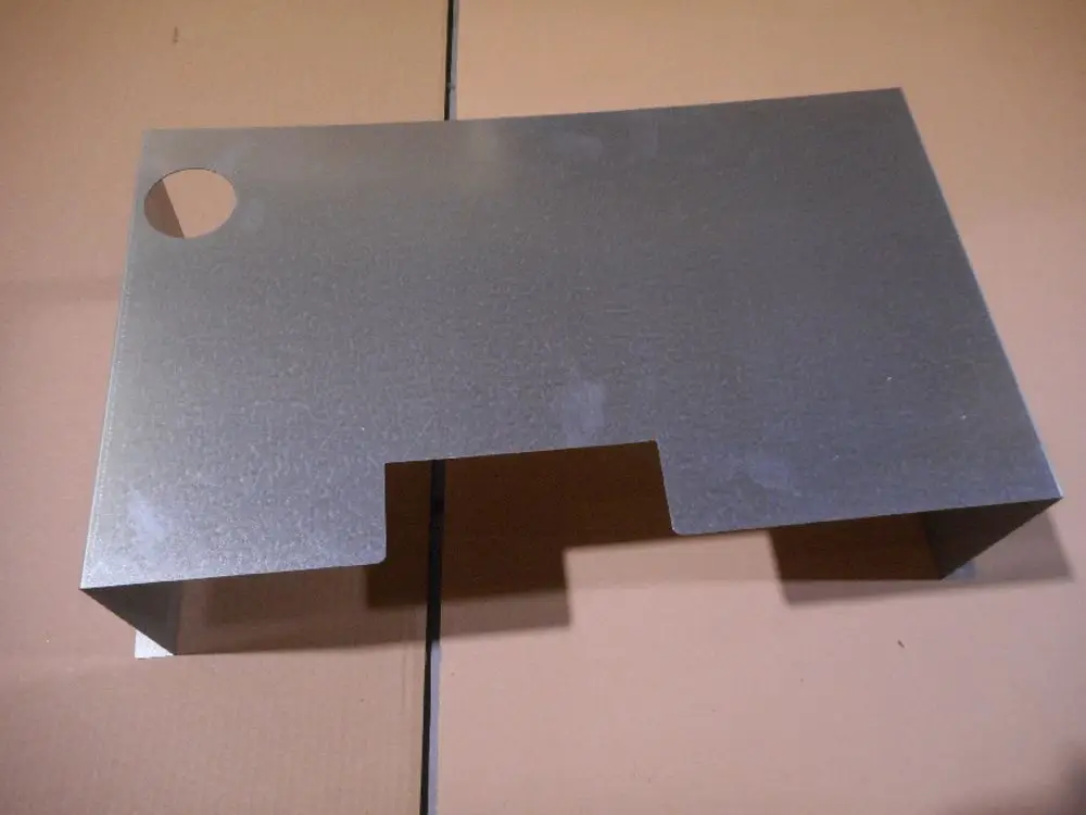 Metallplatte mit ausgeschnittenem Bereich, die als untere Hinterwand dient. Sie gehört zu einem Remeha Produkt und ist auf einer flachen Oberfläche platziert.